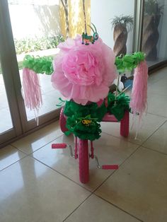 a bicycle made out of pink and green paper flowers sitting on the floor in front of a glass door