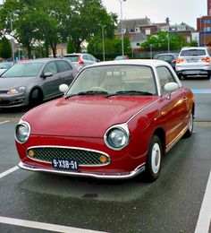 a red car parked in a parking lot next to other cars