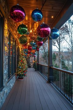 an outdoor covered porch with christmas lights and ornaments hanging from it's ceiling over the deck