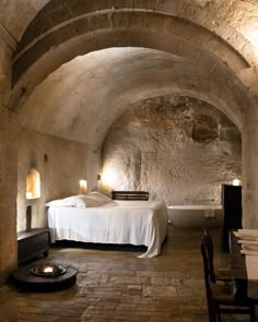 a room with a bed and a bathtub in it that is made out of stone