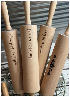 four wooden kitchen utensils with engraved names on them in a wire basket next to a metal container