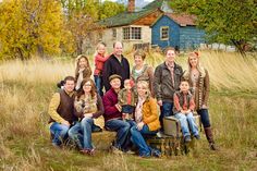 a group of people sitting on top of a wooden bench in a grass covered field