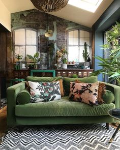 a living room with green couches and pillows on the floor next to potted plants