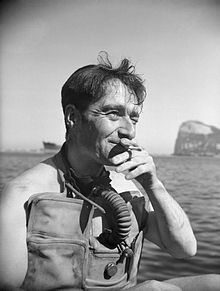 a man sitting on top of a boat while holding a cell phone to his ear