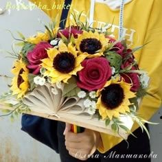 a person holding a bouquet of sunflowers and an open book