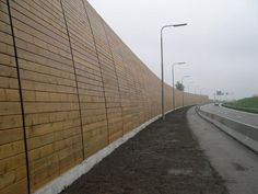 an empty road next to a wooden wall