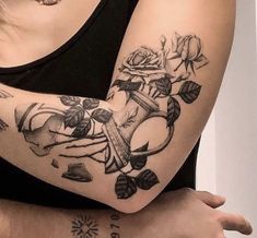 a woman's arm with roses and anchor tattoo on it, while she is wearing a black tank top