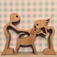 two wooden toy animals are standing on a shelf with checkered wall paper in the background