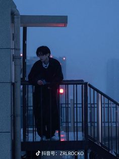 a man standing on top of a balcony next to a metal handrail with lights