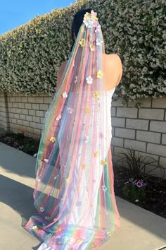 a woman is wearing a veil with flowers on it and standing in front of a brick wall