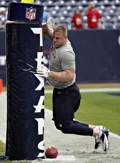 a football player is leaning against a pole on the field with a ball in his hand