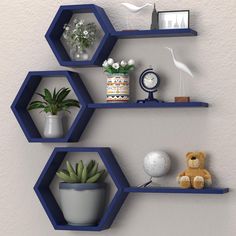 three hexagonal shelves with plants and other items on them against a white wall