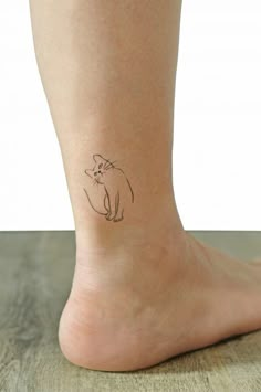 a small tattoo on the ankle of a woman's foot, depicting a cat