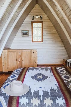 a bed with a blanket and hat on it in a room that has wooden walls