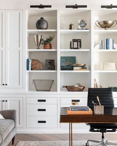 an office with white bookcases filled with books and other items on the shelves