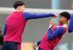 two soccer players standing next to each other with their arms in the air as they practice