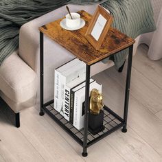 a small end table with books and a cup on it next to a couch in a bedroom