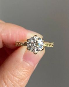 a close up of a person's hand holding a ring with a diamond in it