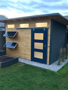 a small shed with solar panels on the roof and windows in the side yard area