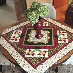 a table with a vase on top of it next to a chair and rugs