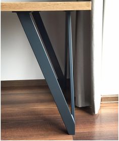 a wooden table sitting on top of a hard wood floor next to a white curtain