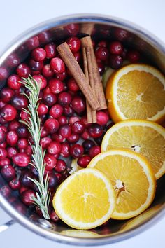 oranges, cranberries and cinnamon sticks are in a pot