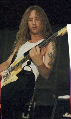 a man with long hair playing an electric guitar