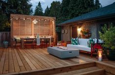 an outdoor deck is lit up with lights and seating for the guests to sit on