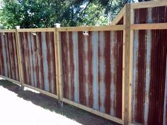 a wooden fence with rusted metal panels