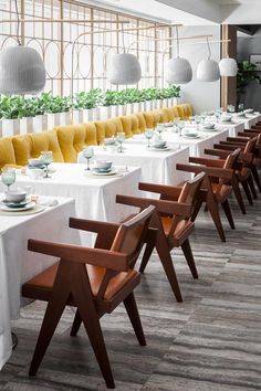 a long table with white and yellow chairs is set up in front of the windows