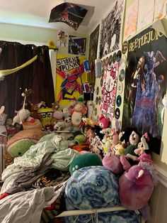 a room filled with lots of stuffed animals on top of blankets and pillow cases next to posters