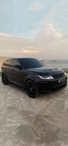 a black range rover parked in front of a body of water