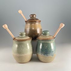 three ceramic jars with wooden spoons in them