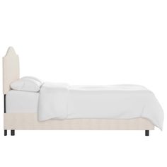 the bed is made up with white sheets and linens on it, while the headboard