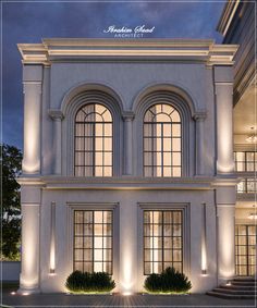 a large white building with three windows and lights on it's front entrance at night