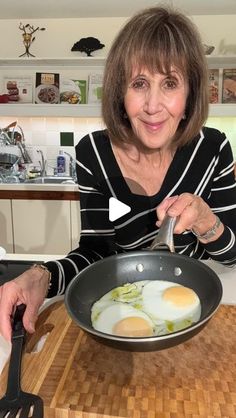 a woman is cooking eggs in a frying pan