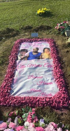 a memorial blanket with two people on it in the grass next to flowers and trees