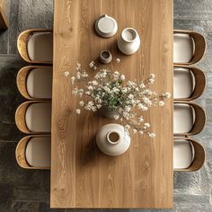 a wooden table topped with white vases and plates