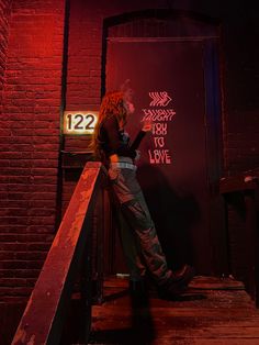 a woman is standing on the stairs looking at her cell phone in front of a neon sign