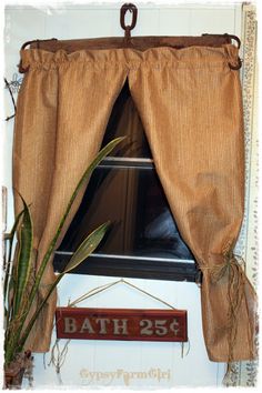 a bathroom window with a plant in it and a bath sign hanging on the wall