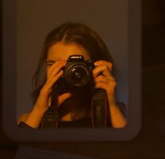 a woman is taking a photo in the mirror with her camera and holding it to her face