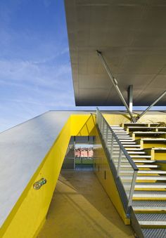 the stairs lead up to the upper level of this modern building with yellow painted walls and metal railings