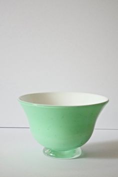 a green bowl sitting on top of a white table