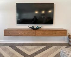 a large flat screen tv mounted to the side of a wooden shelf in a living room