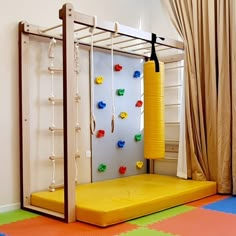 a child's play area with climbing bars and toys on the floor, in front of a curtained window