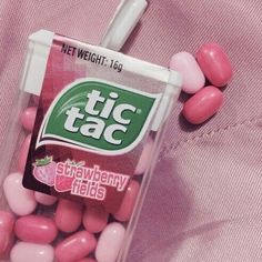 pink and white candy candies in a plastic container with a strawberries logo on it