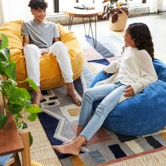 two people sitting on bean bags in a living room with plants and potted plant