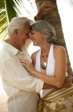 an older couple embracing under a palm tree