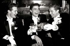 three men in tuxedos are toasting each other