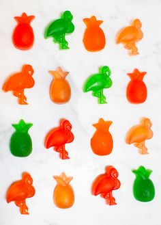 there are many different colored candies in the shape of birds and pears on this marble surface